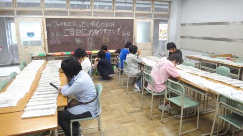 千里高校の文化祭は15時まで。まもなく終了なのでバックナンバーを読みふける報道部員たち。